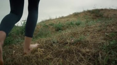 Unknown woman feet walking up green hill close up. Girl climbing on hilltop.