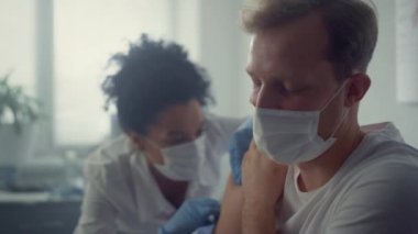 Doktor, sağlık kliniğinde aşıyı yapan hastanın omzuna enjekte ediyor. Aşılama kavramı.