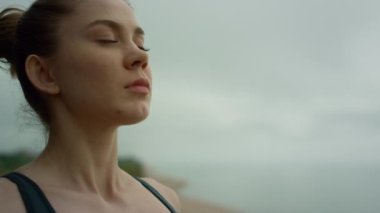 Yogi woman making deep breath meditating on beach. Lady practicing yoga close up