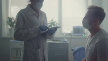 Doctor hands recording results patient checkup on tablet. Doctor consulting man.