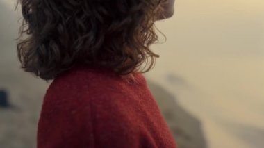 Woman standing sea beach at sunrise. Closeup stylish girl wearing red sweater 