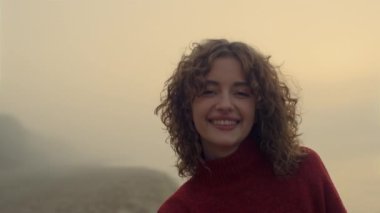 Kameraya poz veren gülümseyen kız. Mutlu kadın güneşin doğuşunda sahilde poz veriyor.