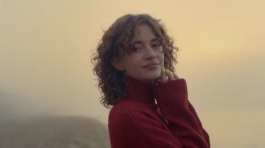 Sabahları sahilde poz veren şehvetli bir kadın. Romantik kız kamerada gülümsüyor.