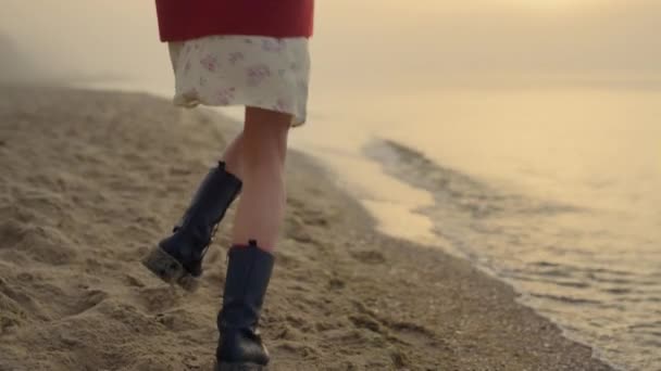 Fille à la mode en bottes sautant sur la plage. Jeune femme pieds tournant autour — Video