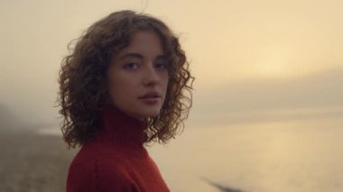 Kameraya poz veren şehvetli bir kadın. Güzel kız deniz kıyısında dinleniyor.