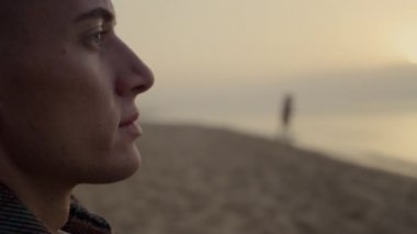 Düşünceli adam gün batımında okyanus manzarasının tadını çıkarıyor. Hayalperest adam göz kırpıyor