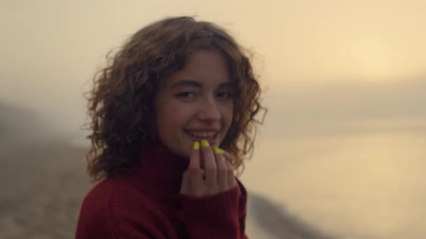 Modieuze vrouw die lacht op de camera. gelukkig meisje poseren bij oceaan strand bij zonsopgang — Stockvideo