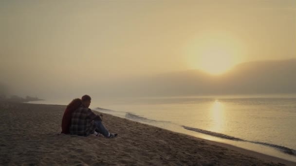 Loving couple sitting on sandy beach at ocean. Young lovers talking together — Stock videók