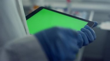 Doktor elleri krom anahtar tabletinde çalışıyor. Eldivenlerle ekrana dokunuyor.