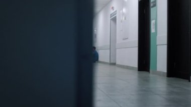 Stressed doctor sitting leaning on wall hallway. Tired medical worker resting.