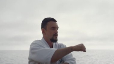 Serious athlete practicing karate closeup. Bearded man workout fighting exercise
