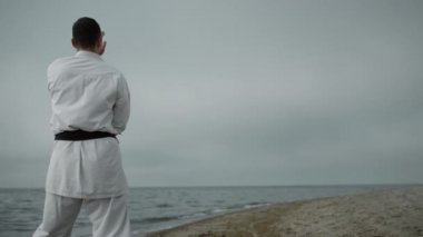 Bulutlu bir günde kumlu sahilde karate eğitimi veren tanınmamış bir sporcu..