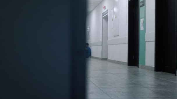 Напружений лікар сидить спираючись на настінний коридор. Втомлений медичний працівник відпочиває . — стокове відео