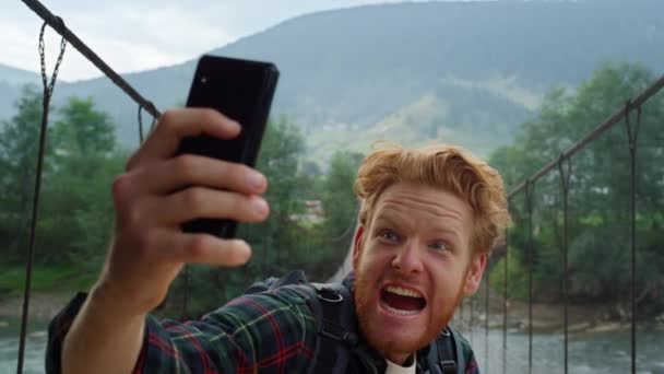 Tourist taking selfie smartphone camera closeup. Guy making funny face on nature — Stock Video