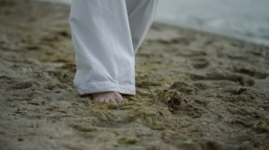 Bilinmeyen çıplak ayaklı bir adam sahile yaklaşıyor. Deniz kenarında egzersiz yapan bir sporcu. 