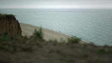 Doğa sahnesi kumlu kıyı şeridi bulutlu bir gün. Karateci adam okyanus dalgaları yakınında çalışıyor..