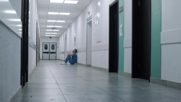 Modern klinikte oturan yorgun cerrah. Doktor hastane koridorunda dinleniyor.. — Stok video