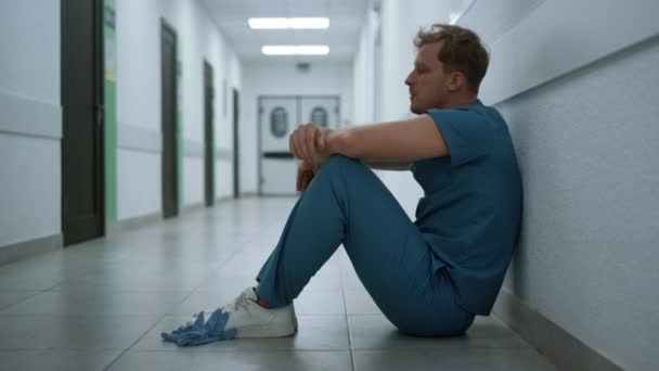 Man surgeon sitting floor clinic hallway closeup. Doctor after hard pandemic day — Video Stock