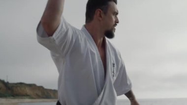 Kung fu ustası sahilde dövüş sanatları eğitimi alıyor. Karate dövüşçüsü antrenmanı.