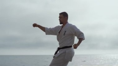 Deniz kıyısına karate tekmesi atan adam yaklaştı. Sporcu dövüş teknikleri.