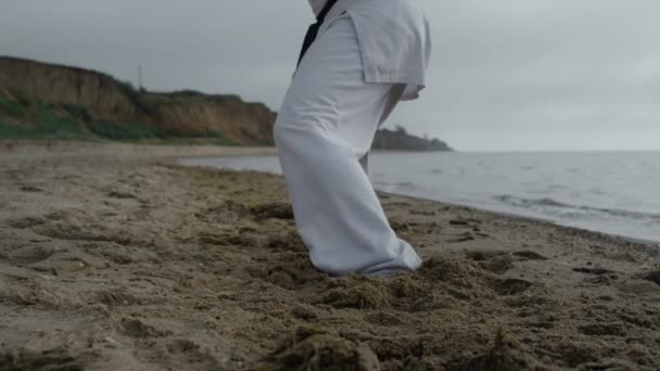 Gambe da primo piano uomo sportivo che esercita spiaggia sabbiosa. Combattente di karate facendo allenamento. — Video Stock