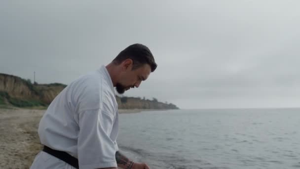 Sporty man doing karate exercise on beach close up. Athlete practicing taekwondo — Wideo stockowe