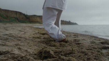 Kumsala ayak basıp karate antrenmanı yapan adam bulutlu havayı yakından takip ediyor..