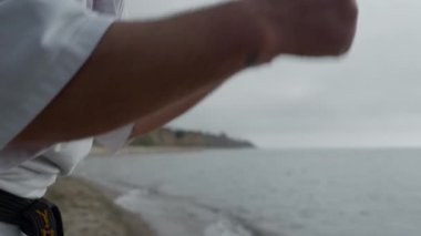 Man fist training karate punches on beach close up. Athlete doing exercises.