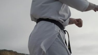Karate dövüşçüsü deniz kıyısında dövüş eğitimi alıyor. Tekvando çalışan bir adam..