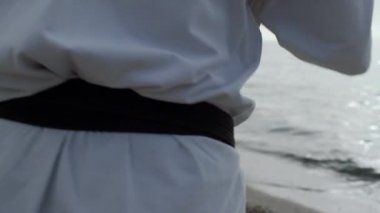 Strong man exercising karate punches close up. Sportsman training on sandy beach