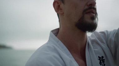 Kapanış adamı okyanus kenarında karate eğitimi alıyor. Eller dövüş egzersizleri yapıyor..