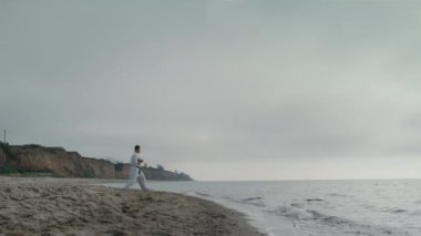 Karate sporcusu, kumsalda saldırı pratiği yapıyor. Güçlü adam dışarıda antrenman yapıyor.