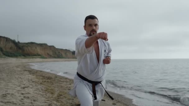 Karate man training fighting skills on sandy beach close up — Stock videók