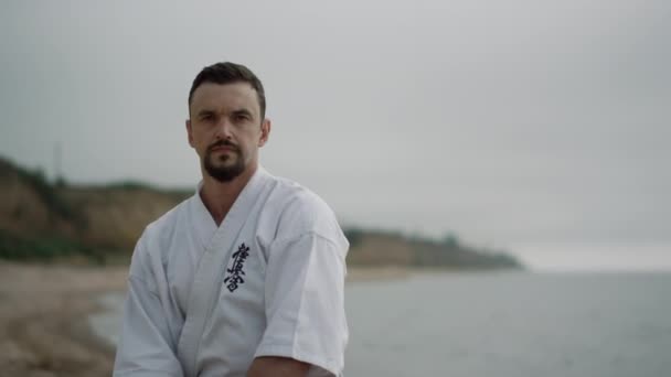 Fit boxeador entrenamiento golpes de karate en la playa. Hombre aprendizaje técnicas de combate. — Vídeo de stock
