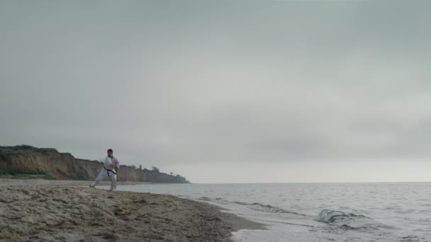 Professional karate man training on sandy beach. Athlete practicing taekwondo. — Stock Video