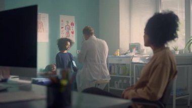 Doctor measuring pressure african teen girl with stethoscope in mother presence.
