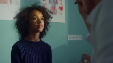 Pediyatrist nörolojik refleksli genç kızı el feneriyle yakından kontrol ediyor..