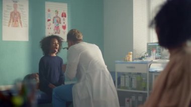 Doctor examining girl throat in hospital. Mom bring teen kid to pediatrician.