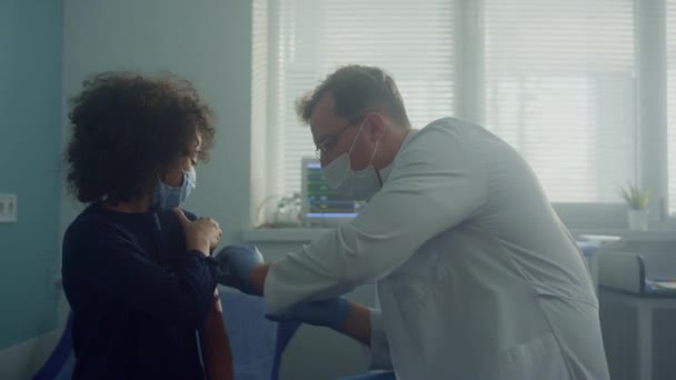 医師は、クリニックでワクチンを与える前の患者を免疫化します。女の子を注射する男. — ストック動画