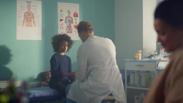 Médico colocando oxímetro de pulso na menina paciente dedo sentado clínica com a mãe. — Vídeo de Stock