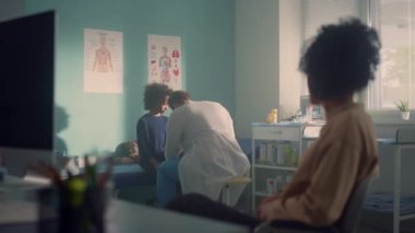 Anne kızını muayenehanede bekliyor. Afrikalı kız doktoru ziyaret etti.