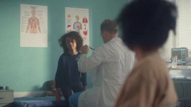 Physician checking teen girl lungs with stethoscope. Kid visit pediatrician.