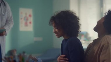 Afrikalı bir aile modern ofiste çocuk doktorunu ziyaret ediyor. Doktor muayeneye başla.