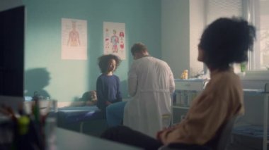 Man doctor giving medical advice african mother after examining teen daughter.