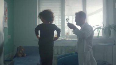 Modern klinikte steteskop kullanan doktor genç kızların ciğerlerini dinliyor.