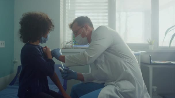 Professionelle Mediziner injizieren Covid-Impfstoff an afrikanisches amerikanisches Kind aus nächster Nähe. — Stockvideo