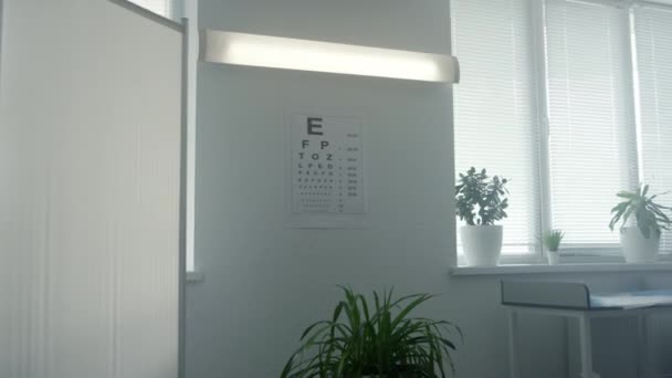Tableau standard de test de la vue suspendu mur blanc dans le bureau du médecin gros plan. — Video