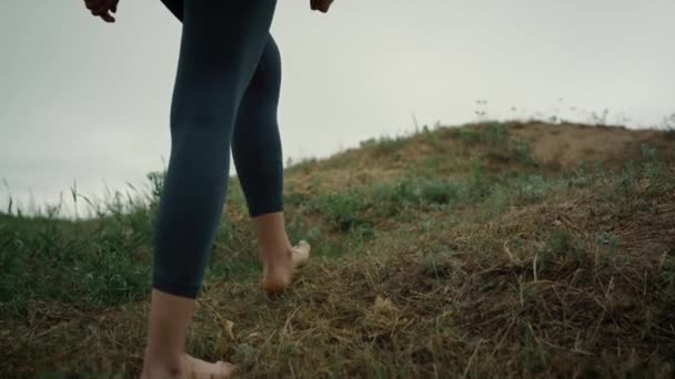 Sportief meisje gaat heuvel rand close-up. Vrouw benen wandelen heuveltop bewolkt dag. — Stockvideo