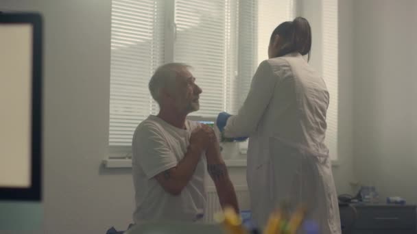 Kvinna läkare förbereda patienten axeln att injicera vaccin på moderna sjukhus. — Stockvideo