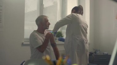 Hekim yaşlı hastayı hastanede aşılıyor. Yaşlı adam aşı oluyor..